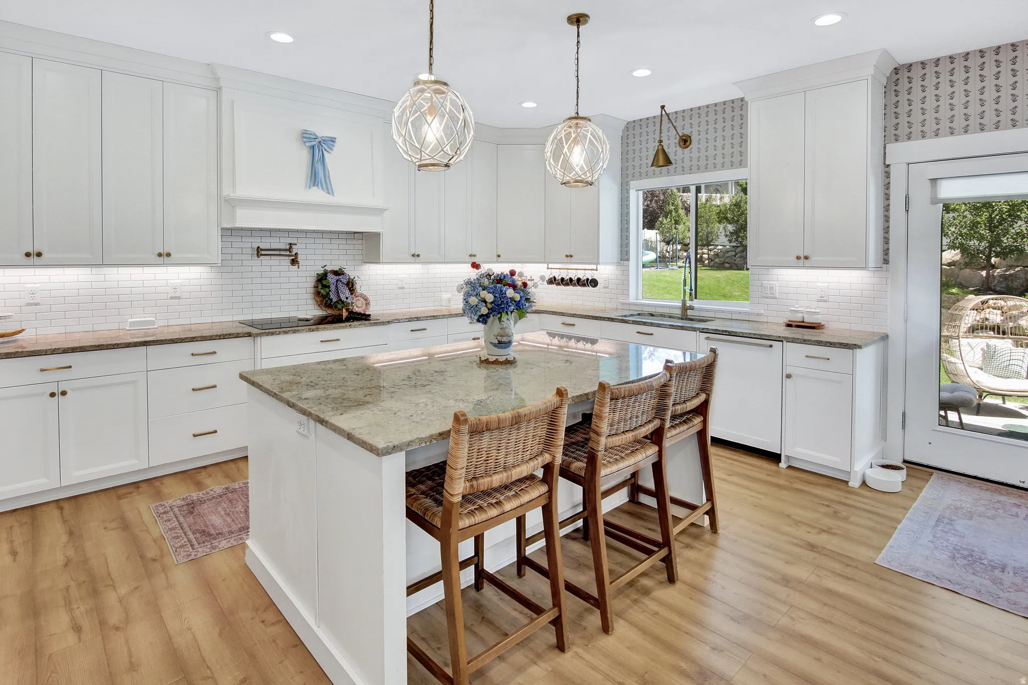 Spacious kitchen featuring an expansive island with a granite countertop, white shaker-style cabinetry, subway tile backsplash, recessed lighting, and wood-finish flooring