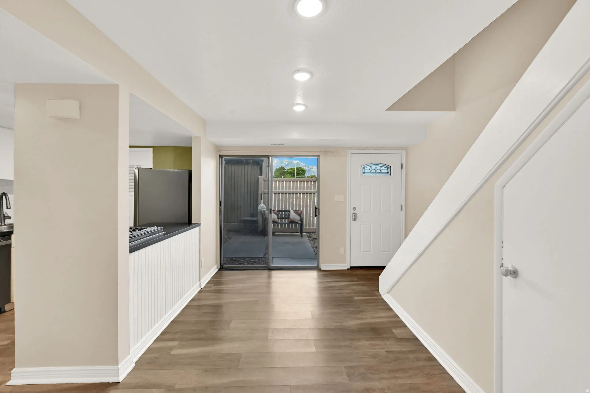 Spacious open-concept living area featuring wood-finish flooring, recessed lighting, and a sliding glass door to the patio