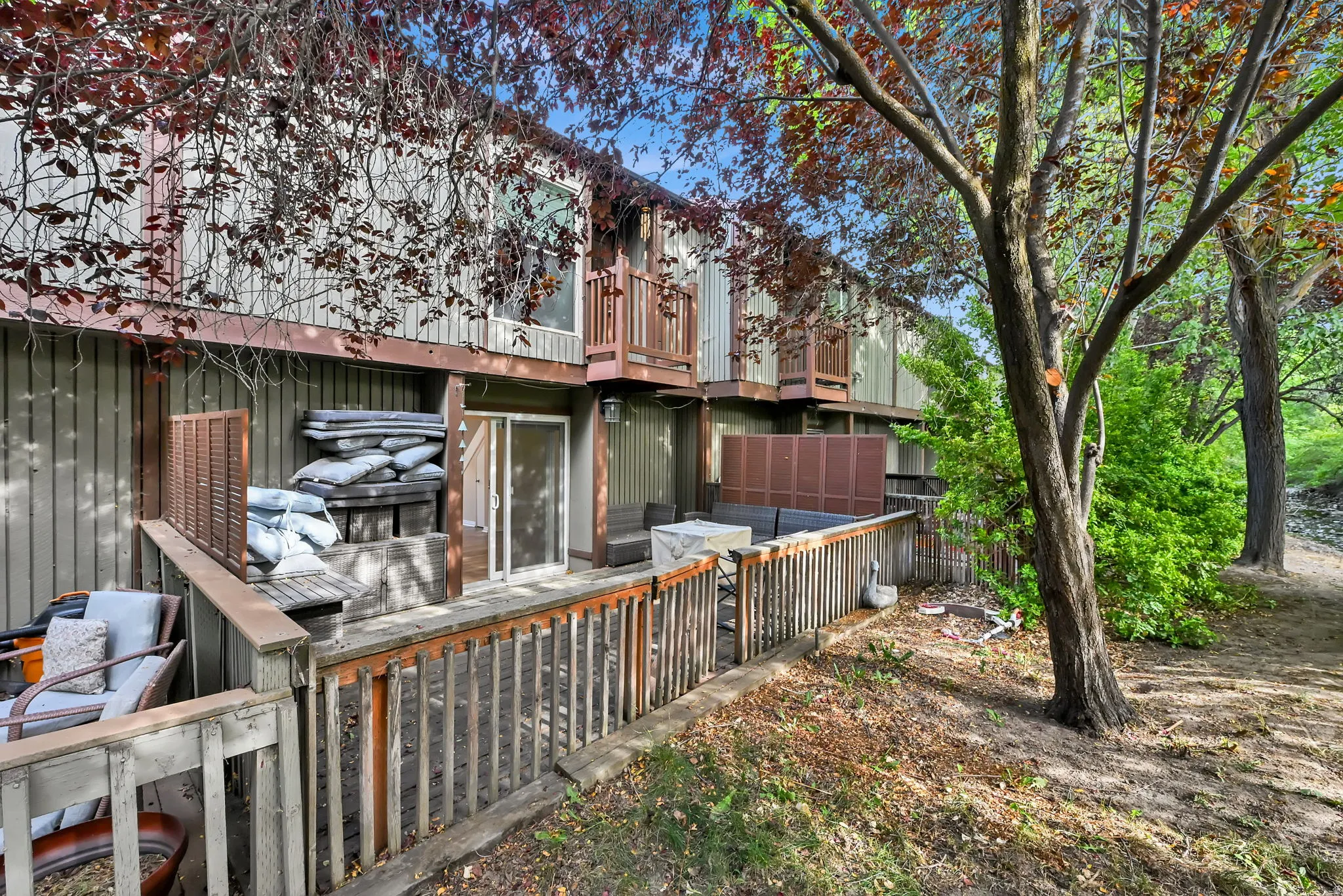 Multi-level wood deck with slatted railings, a sliding glass door, and an upper-level balcony