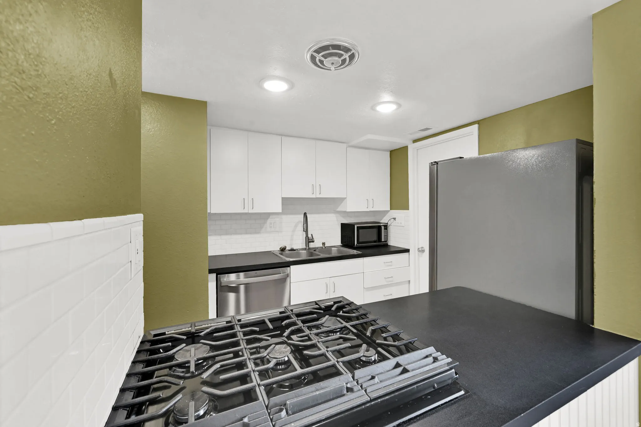 Kitchen featuring a gas range, white cabinetry, dark countertops, a stainless steel dishwasher, and a subway tile backsplash