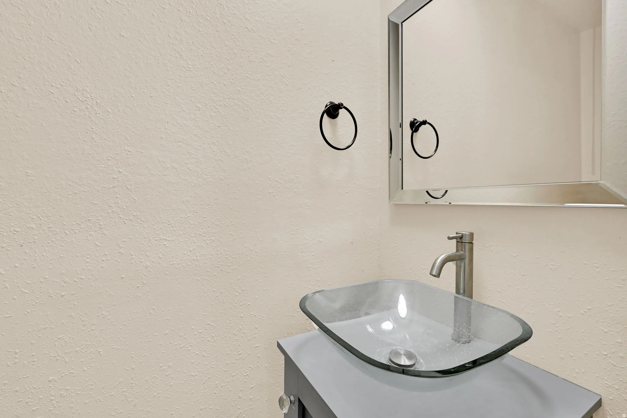 Contemporary vessel sink with clear glass basin and brushed nickel faucet