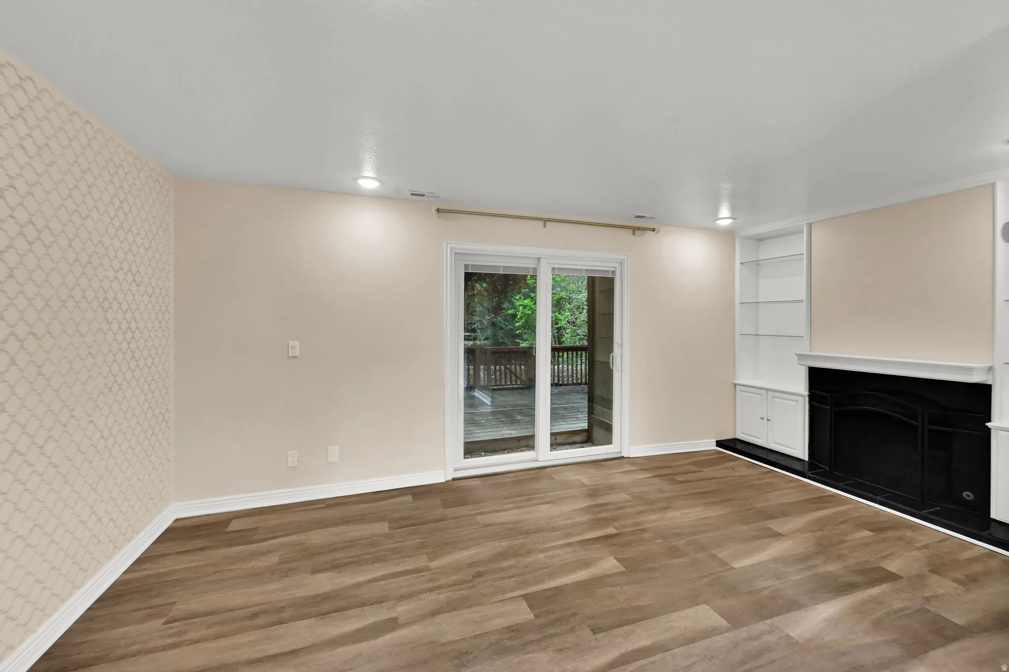 Spacious room featuring wood-finish flooring and a decorative accent wall