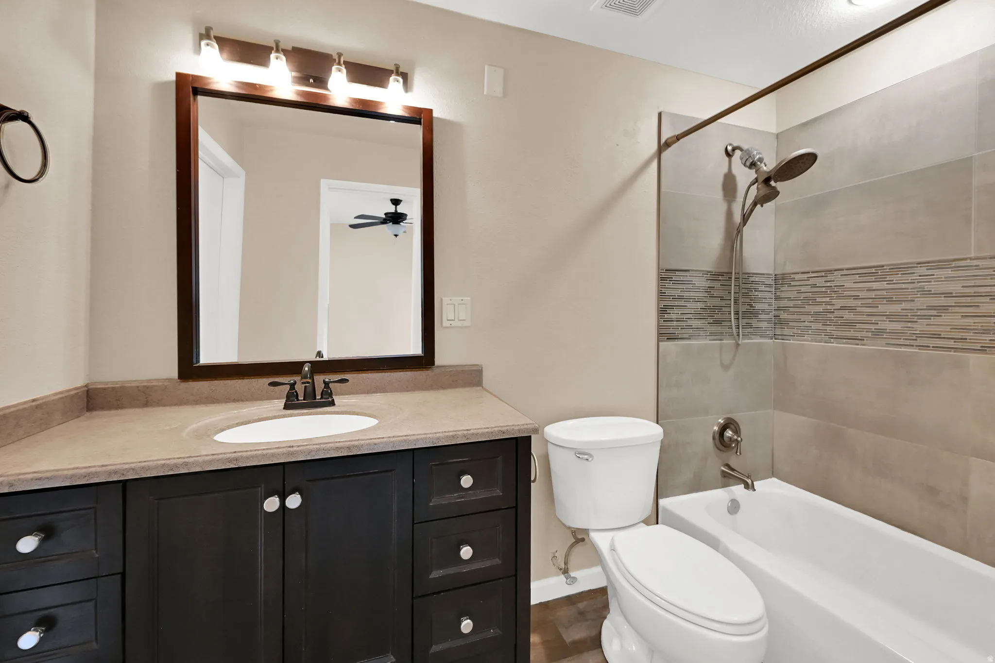 Bathroom featuring a dark wood-finish vanity with a light-toned countertop, an undermount sink, and a framed mirror