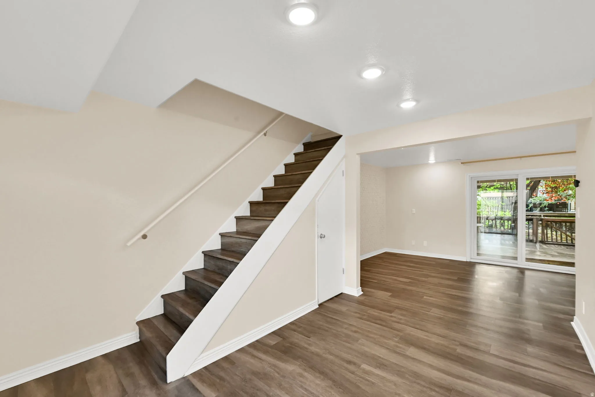 Lower level living area featuring wood-finish flooring, recessed lighting, and a sliding glass door leading to an outdoor deck