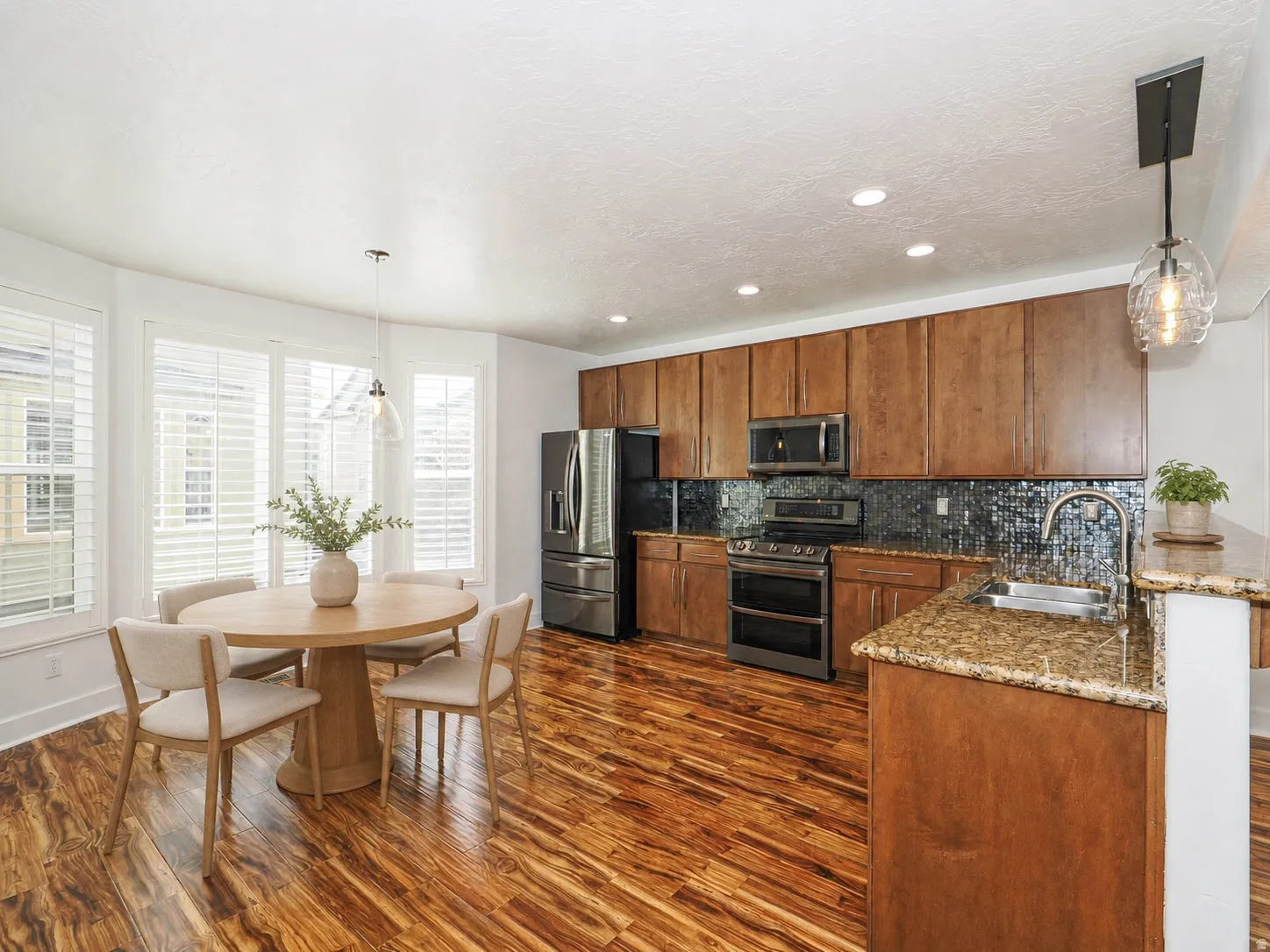 Kitchen featuring stainless steel appliances, wood-finish cabinetry, granite countertops, and a mosaic tile backsplash