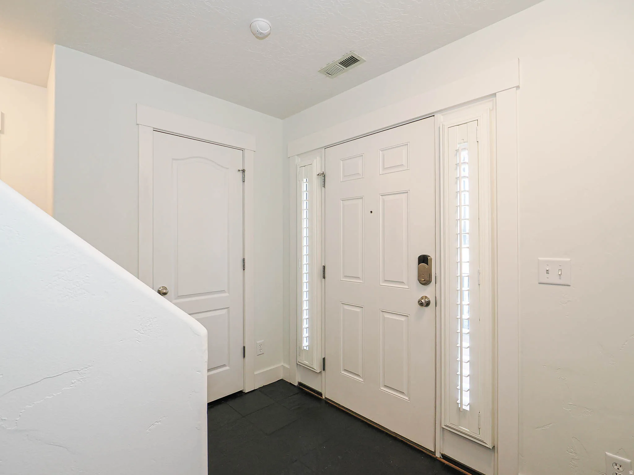 Entryway featuring a paneled door with sidelight, dark tile flooring, and white trim