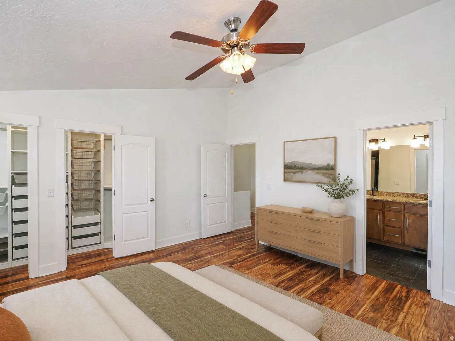 Spacious room featuring vaulted ceilings, wood-finish flooring, and a ceiling fan