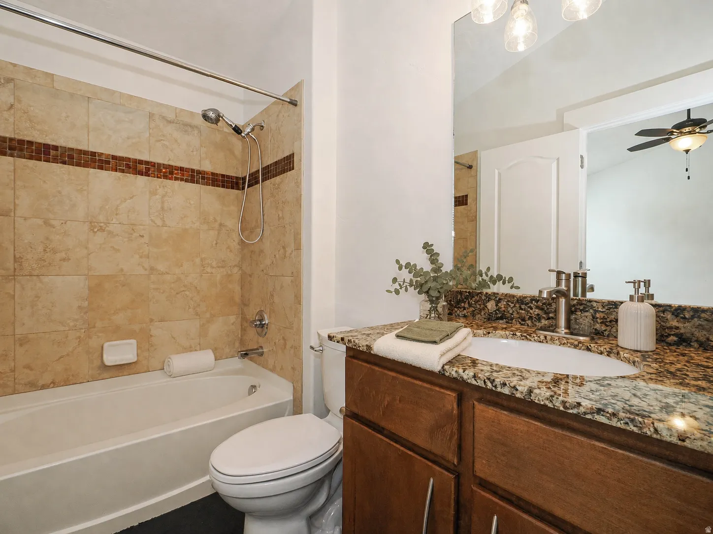 Bathroom featuring a full vanity with an undermount sink, a granite-finish countertop, and wood-finish cabinetry