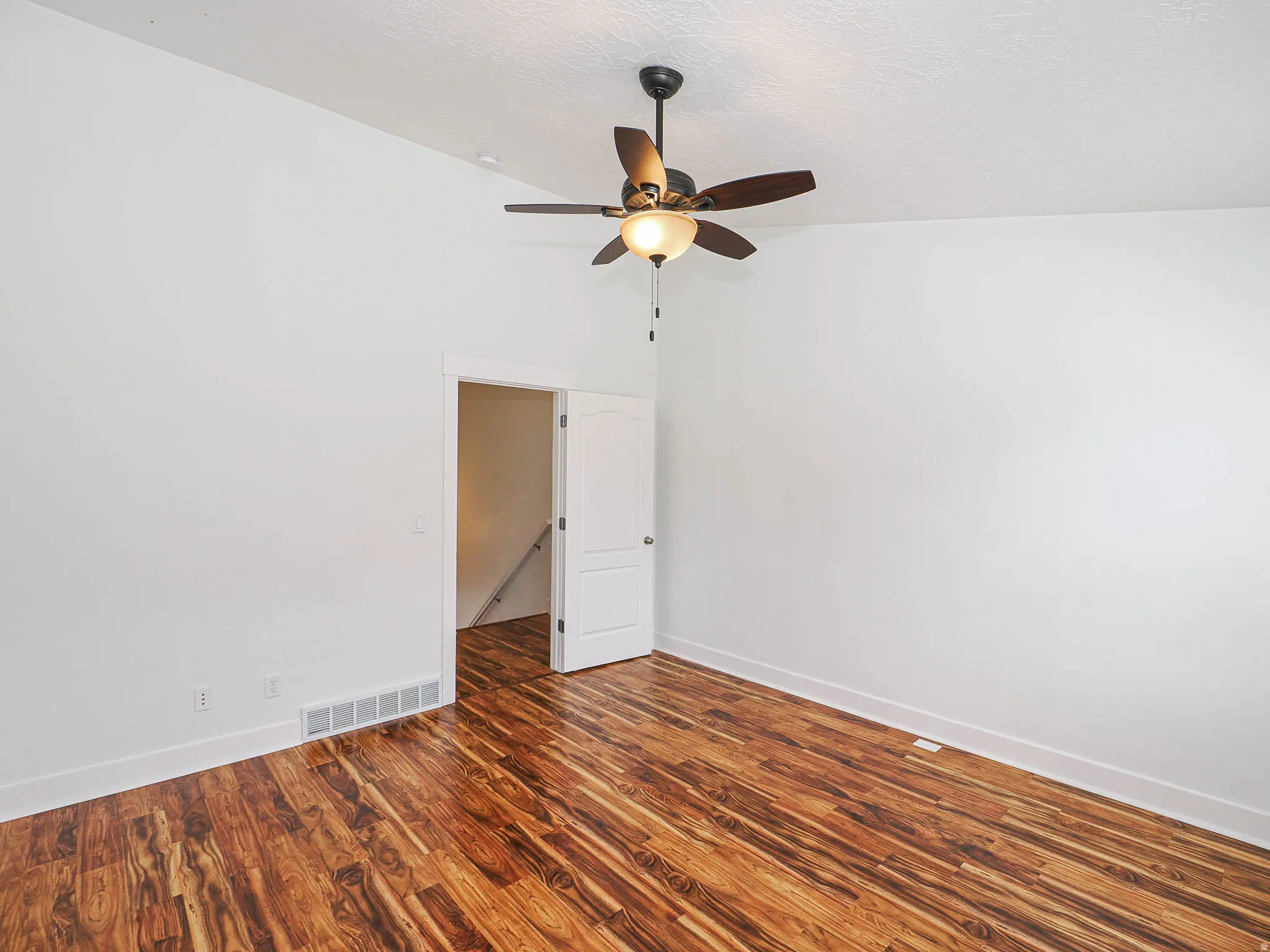 Vaulted ceiling room featuring wood-finish flooring and a ceiling fan with integrated lighting