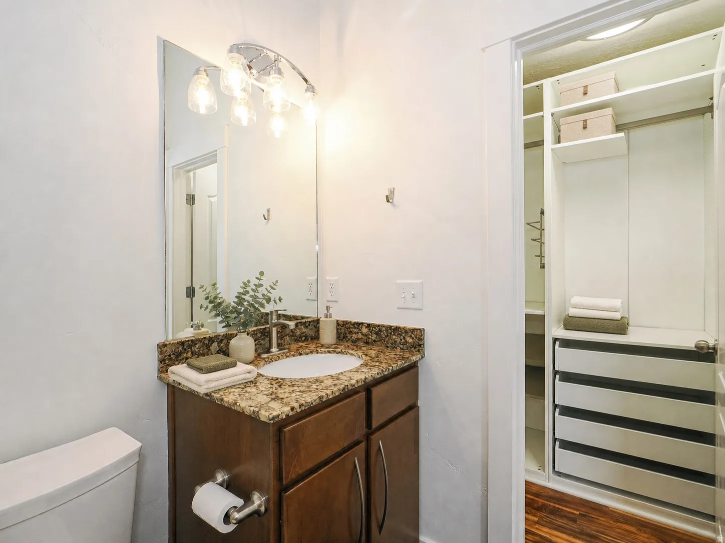 Vanity featuring a stone-look countertop, integrated sink, and dark wood-finish cabinetry
