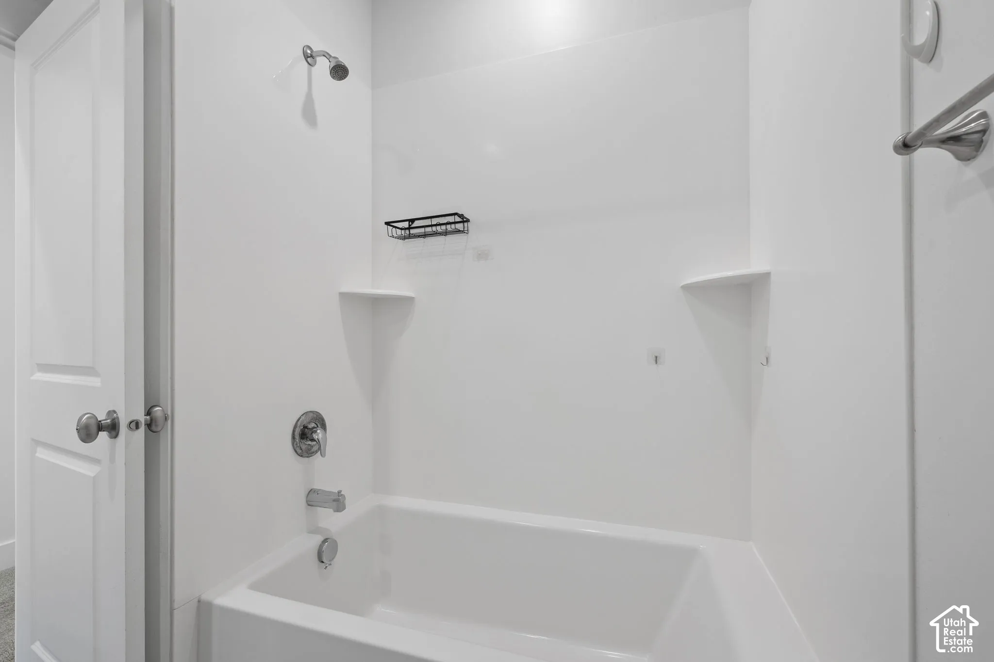 White tub and shower combination with a single showerhead and integrated shelving