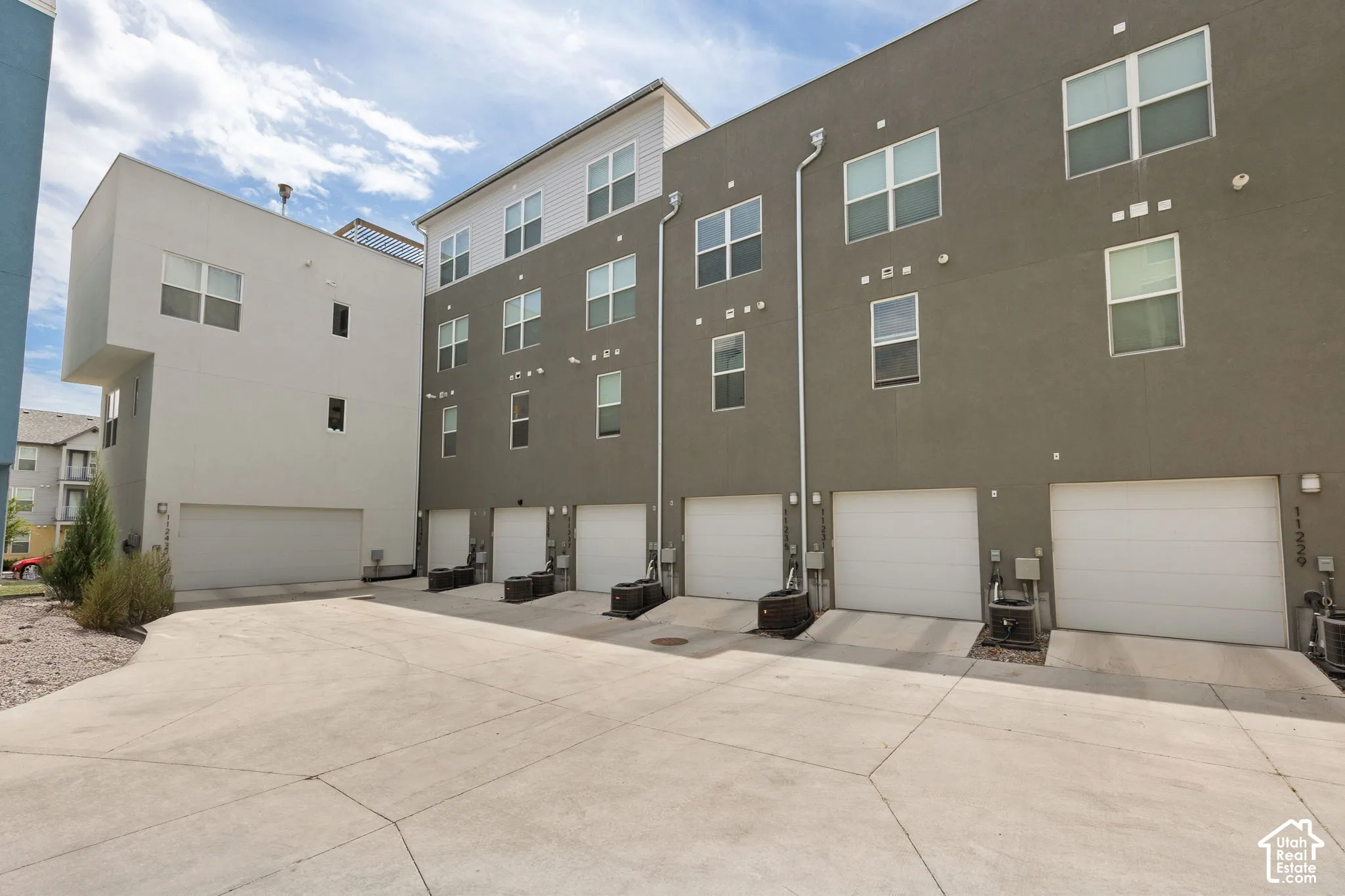 Modern multi-story townhomes with a concrete driveway and multiple garage bays