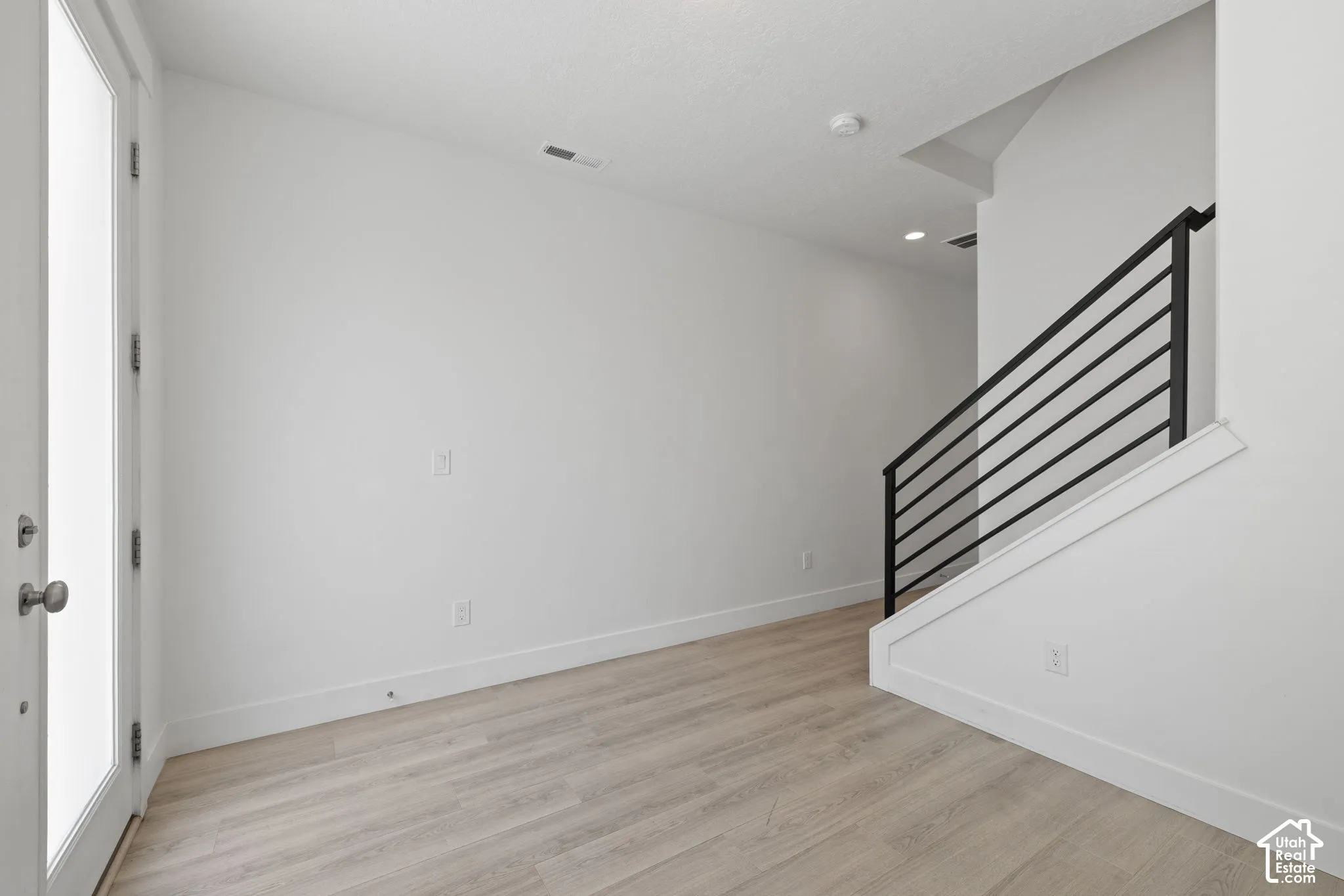 Bright entry/office room featuring light wood-finish flooring, neutral color scheme and natural light