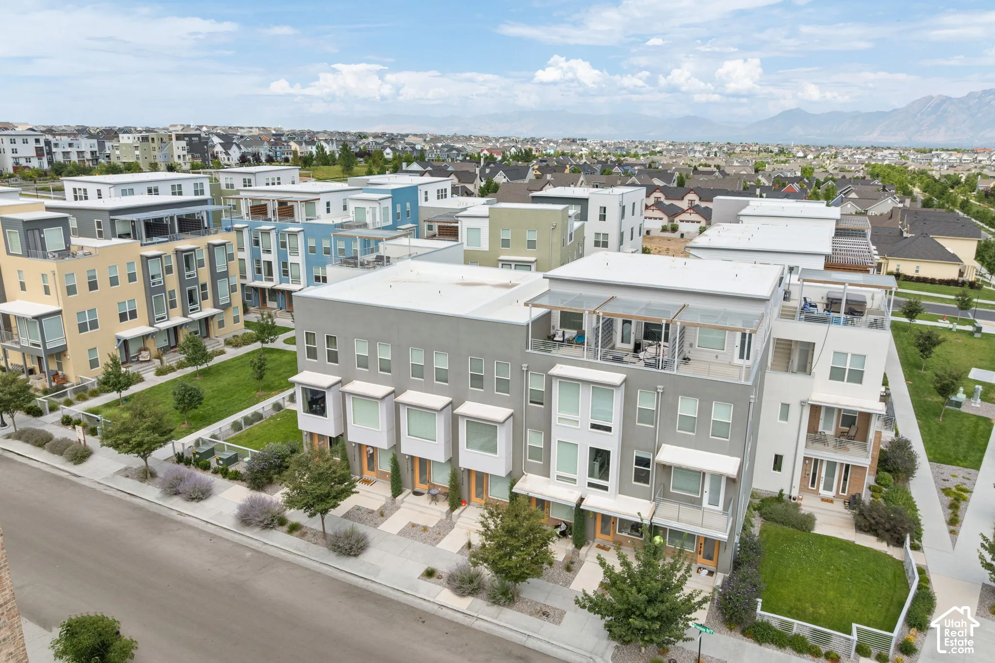 Modern townhome facade featuring a flat roofline, stucco exterior, bay windows, and private balconies