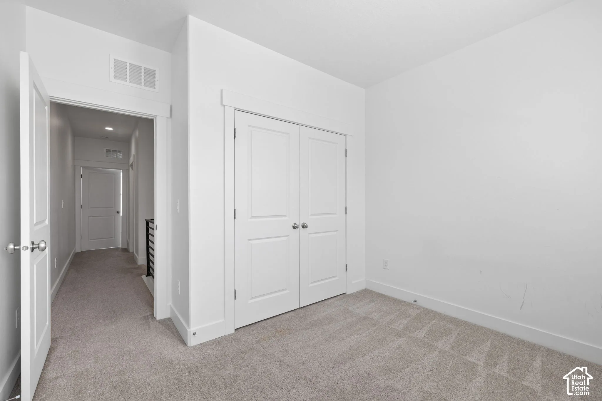 West facing bedroom featuring two windows with blinds, light-colored carpet, white walls, and white baseboards, abundant natural light