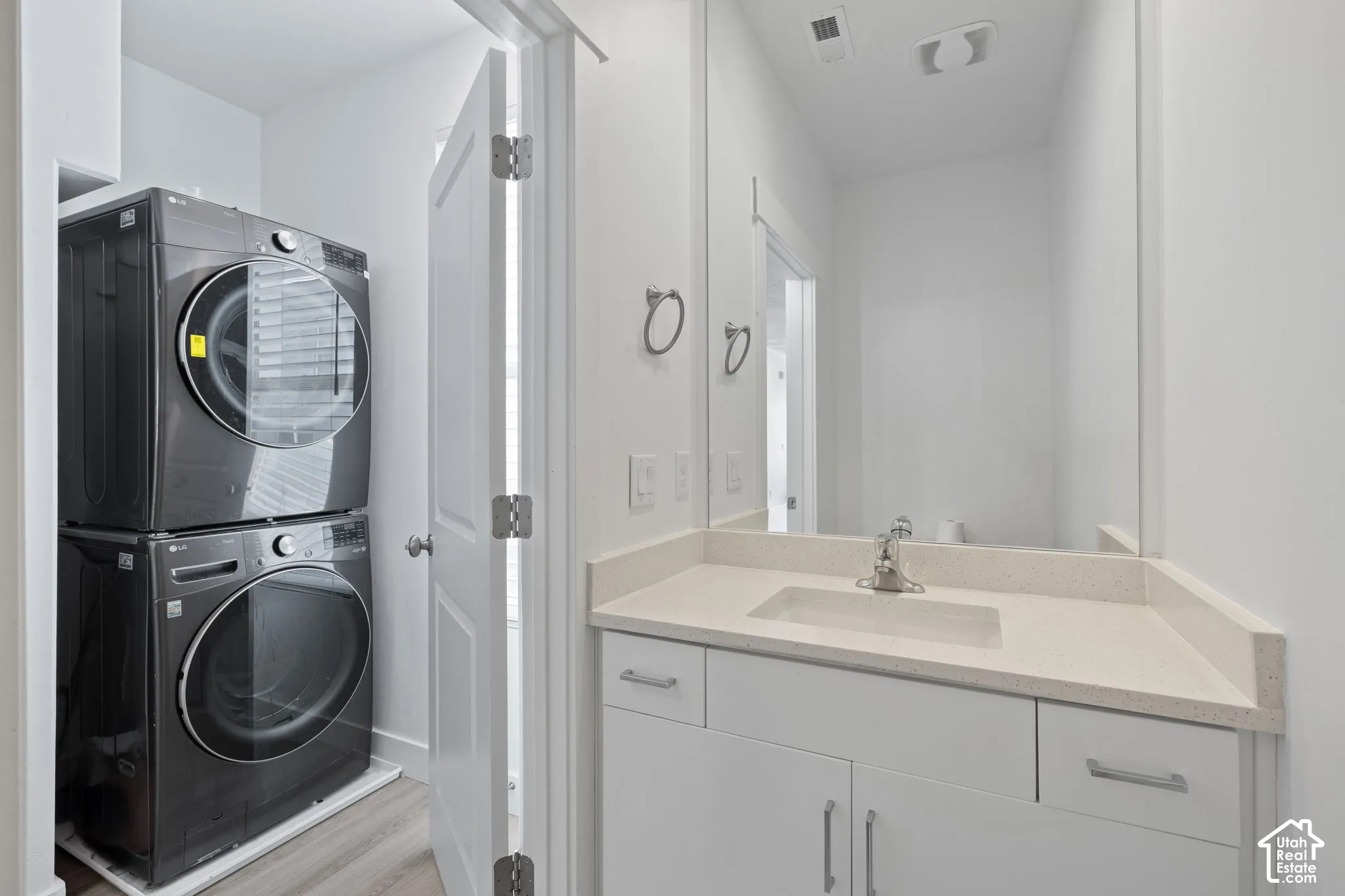 View from bathroom featuring vanity with white cabinetry and quartz counters, with dedicated laundry area just outside