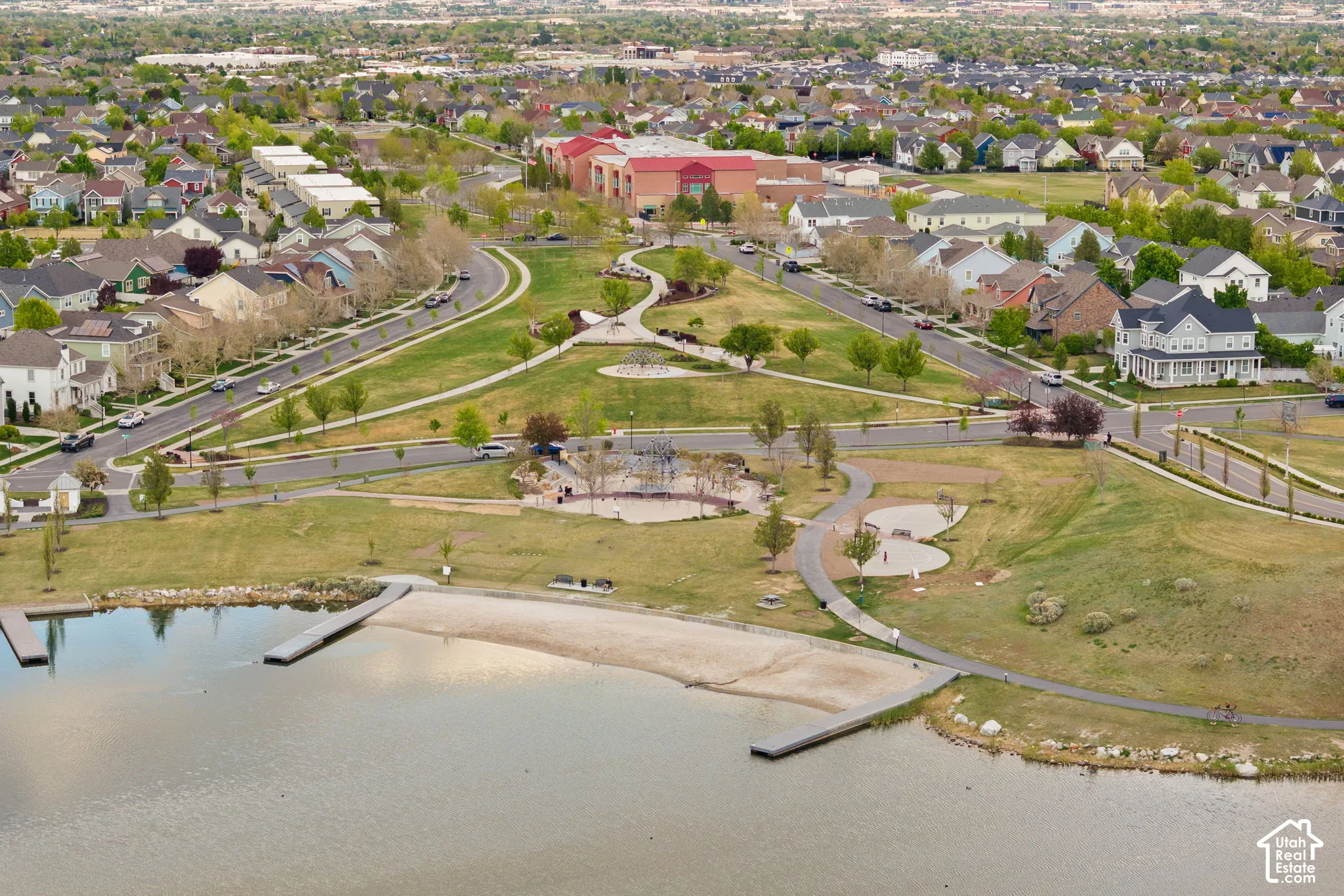 Aerial perspective showcasing a community park with a waterfront, sandy beach area, and two docks