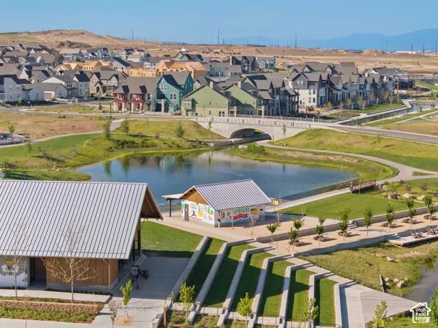 Community park featuring a large pond, pedestrian bridge, and structured outdoor seating areas