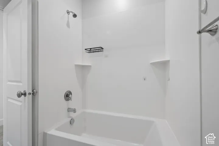 White tub and shower combination with a single showerhead and integrated shelving