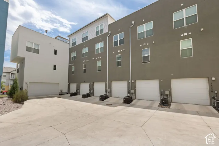 Modern multi-story townhomes with a concrete driveway and multiple garage bays