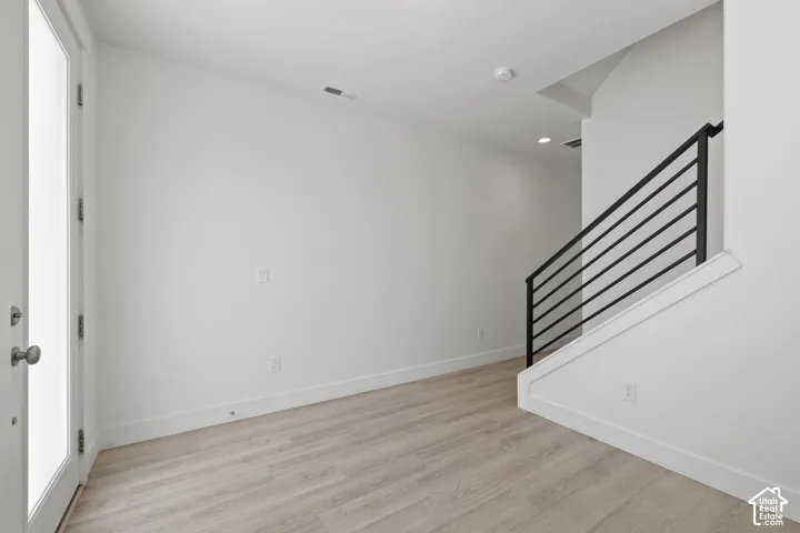 Bright entry/office room featuring light wood-finish flooring, neutral color scheme and natural light