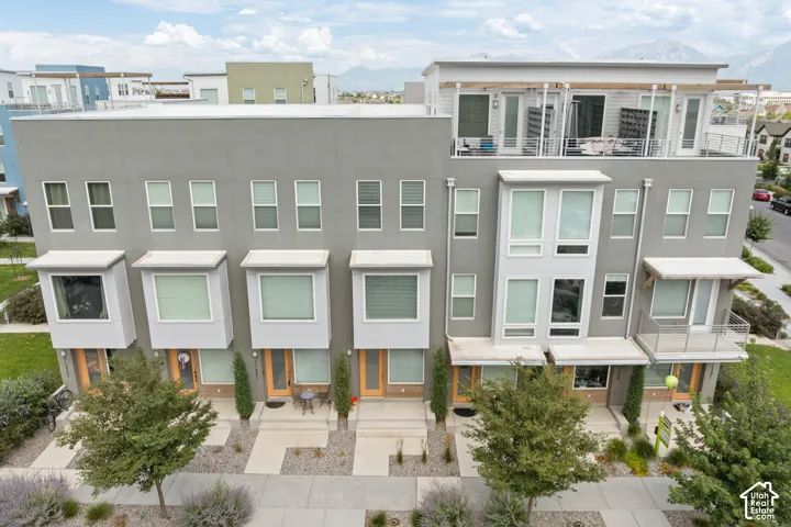 Modern townhome facade featuring a flat roofline, stucco exterior, bay windows, and private balconies