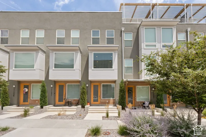 Contemporary multi-level townhome featuring a stucco exterior and wood-finish entry doors