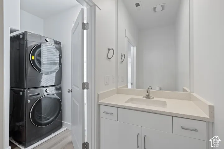 View from bathroom featuring vanity with white cabinetry and quartz counters, with dedicated laundry area just outside