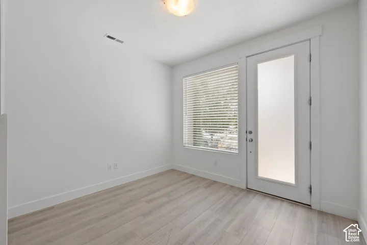 Bright entry/office room featuring light wood-finish flooring, neutral color scheme and natural light