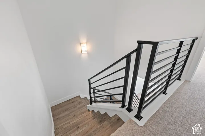 View of stairwell with wood-finish LVP stair treads and modern black horizontal railing