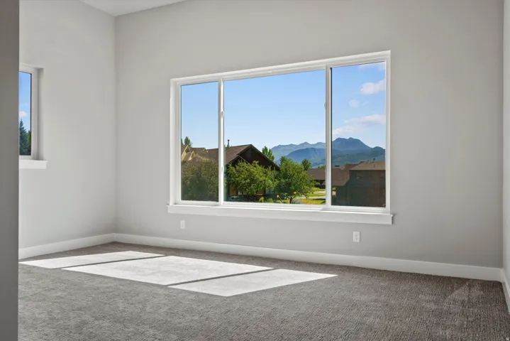 Bright, light-filled room with expansive triple-pane windows framing mountain vistas and landscaped grounds