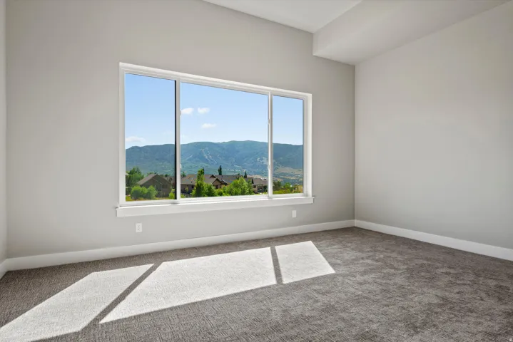 Bright corner bedroom with expansive multi-pane windows framing mountain and landscape vistas