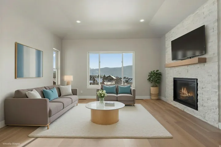 Light-filled living area featuring wood-finish flooring, a contemporary fireplace with a stone surround, and recessed ceiling lighting