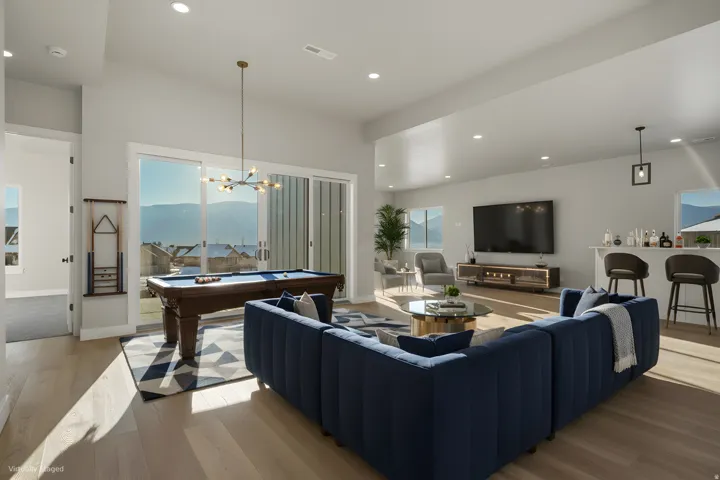 Expansive recreation room featuring a wood-finish floor, wall-mounted television, built-in media cabinetry, and a full billiards table