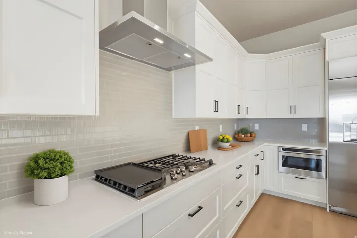 White shaker cabinetry with black hardware, stainless steel gas range, built-in microwave, light-toned tile backsplash, and light wood-finish flooring