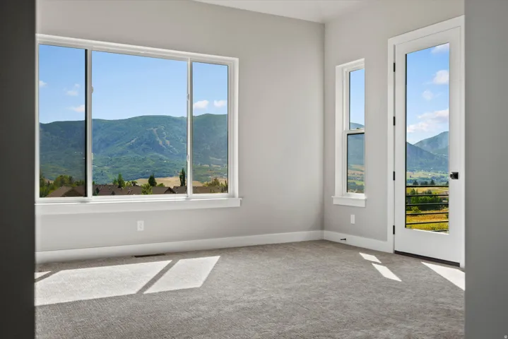 Expansive window wall with a sliding door, light gray wall paint, and gray carpet flooring