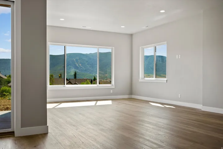 Expansive windows showcasing mountain scenery, wood-finish flooring, recessed lighting, and a neutral wall palette