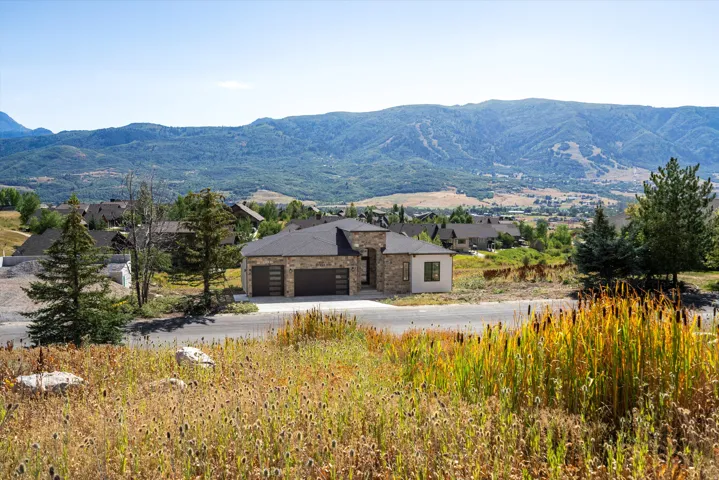 Modern residence with stone and stucco exterior, situated on expansive grounds with native plantings and mature evergreen trees