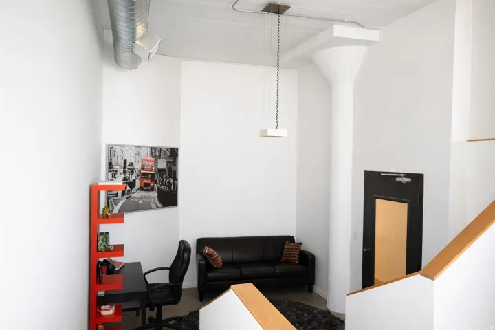 Loft-style living area featuring high ceilings with exposed ductwork, a structural column, and a modern pendant light fixture