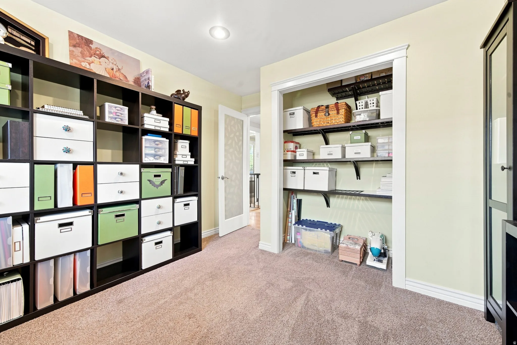 Versatile interior space featuring recessed lighting, plush carpet flooring, a built-in closet with adjustable shelving, and a glass-paneled interior door