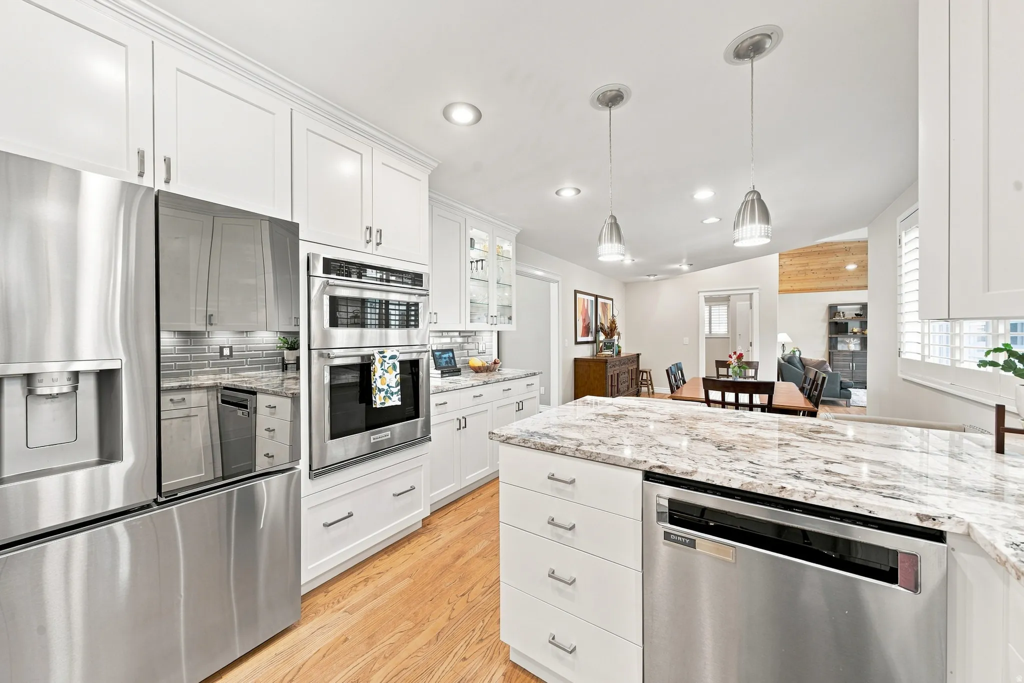 Spacious kitchen featuring white cabinetry, stainless steel appliances, granite countertops, wood-finish flooring, and recessed lighting