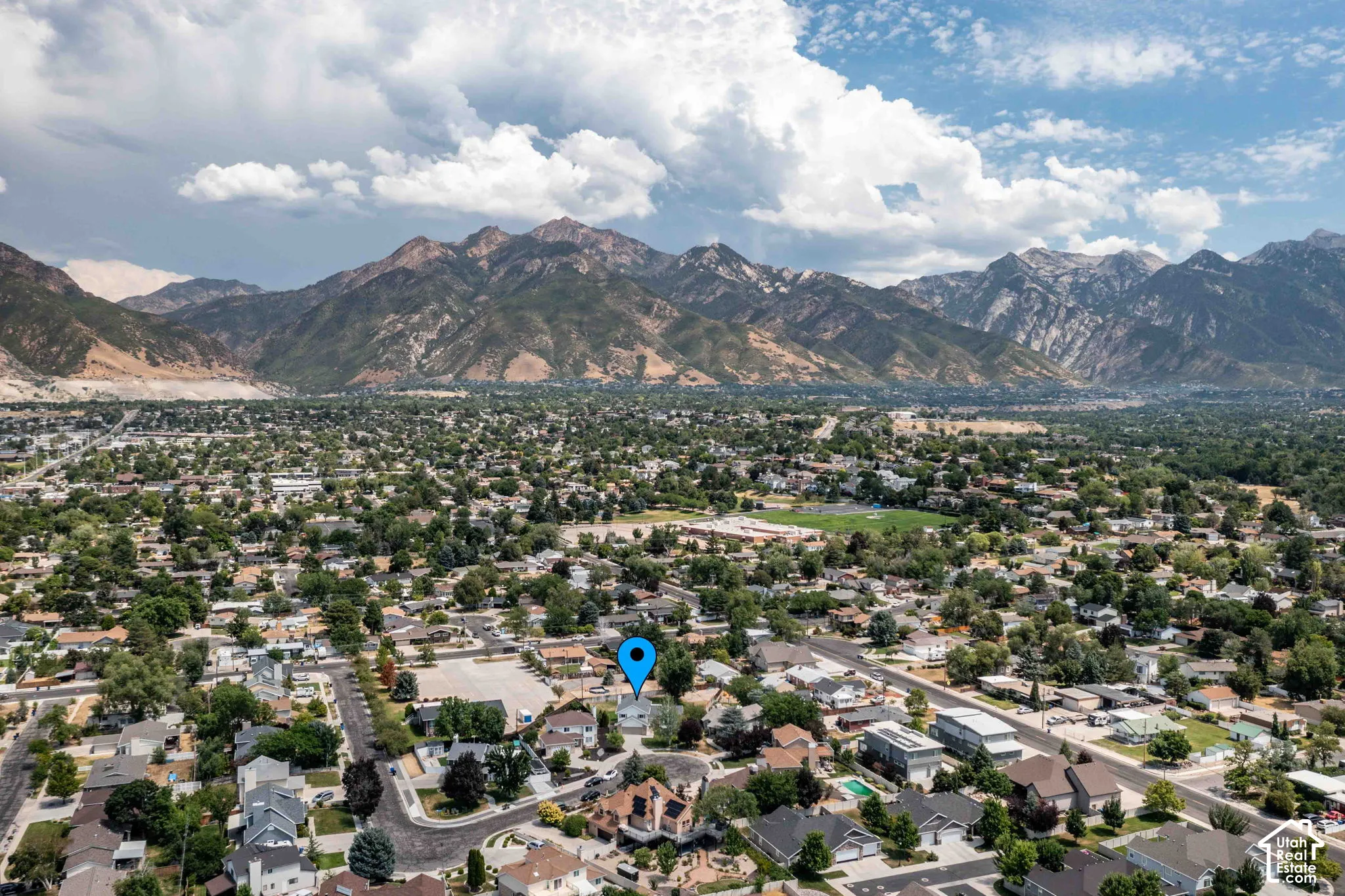 Expansive aerial perspective showcasing a residential neighborhood with abundant mature trees and mountainous terrain