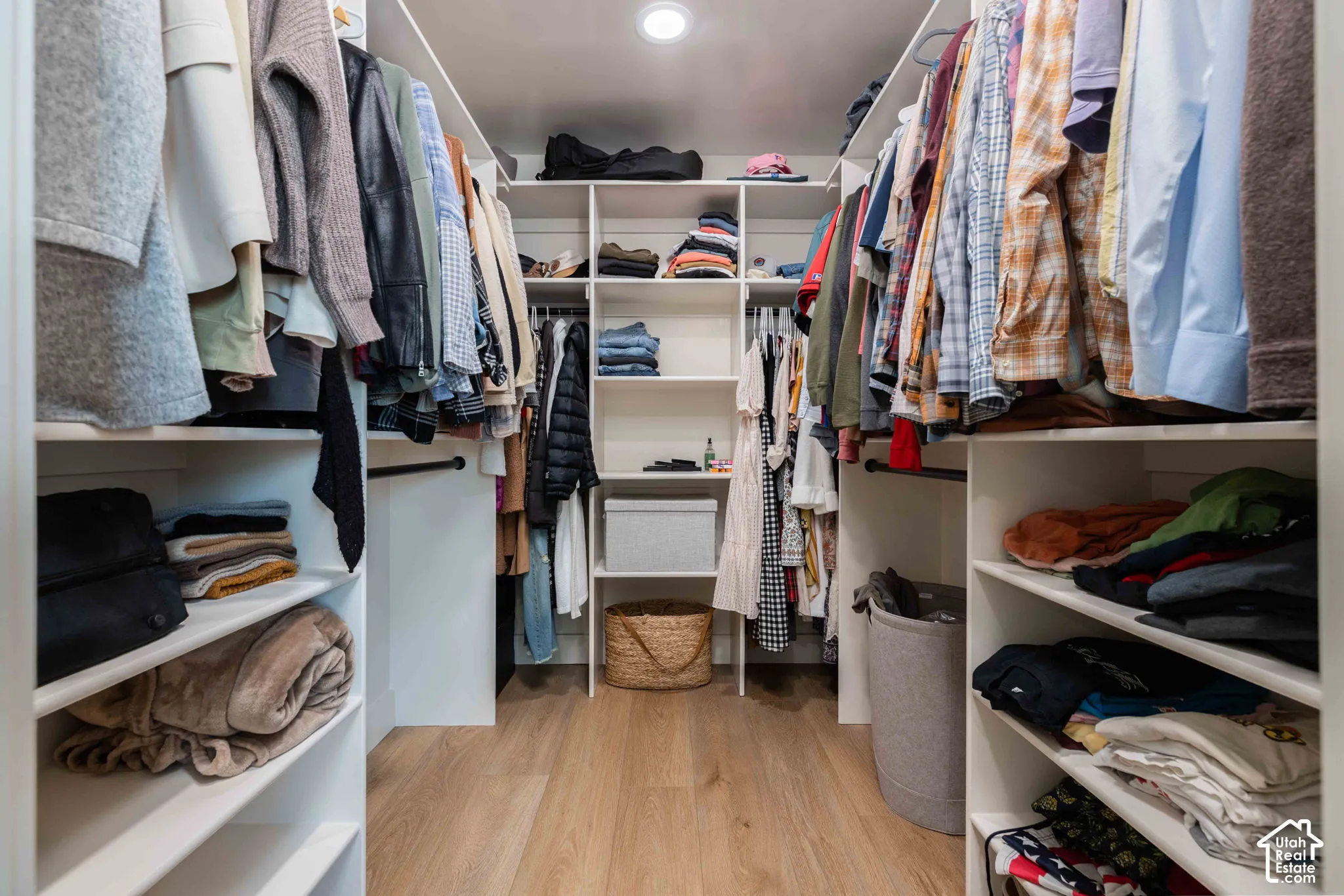 Walk-in closet featuring built-in white shelving, multiple hanging rods, recessed lighting, and wood-finish flooring