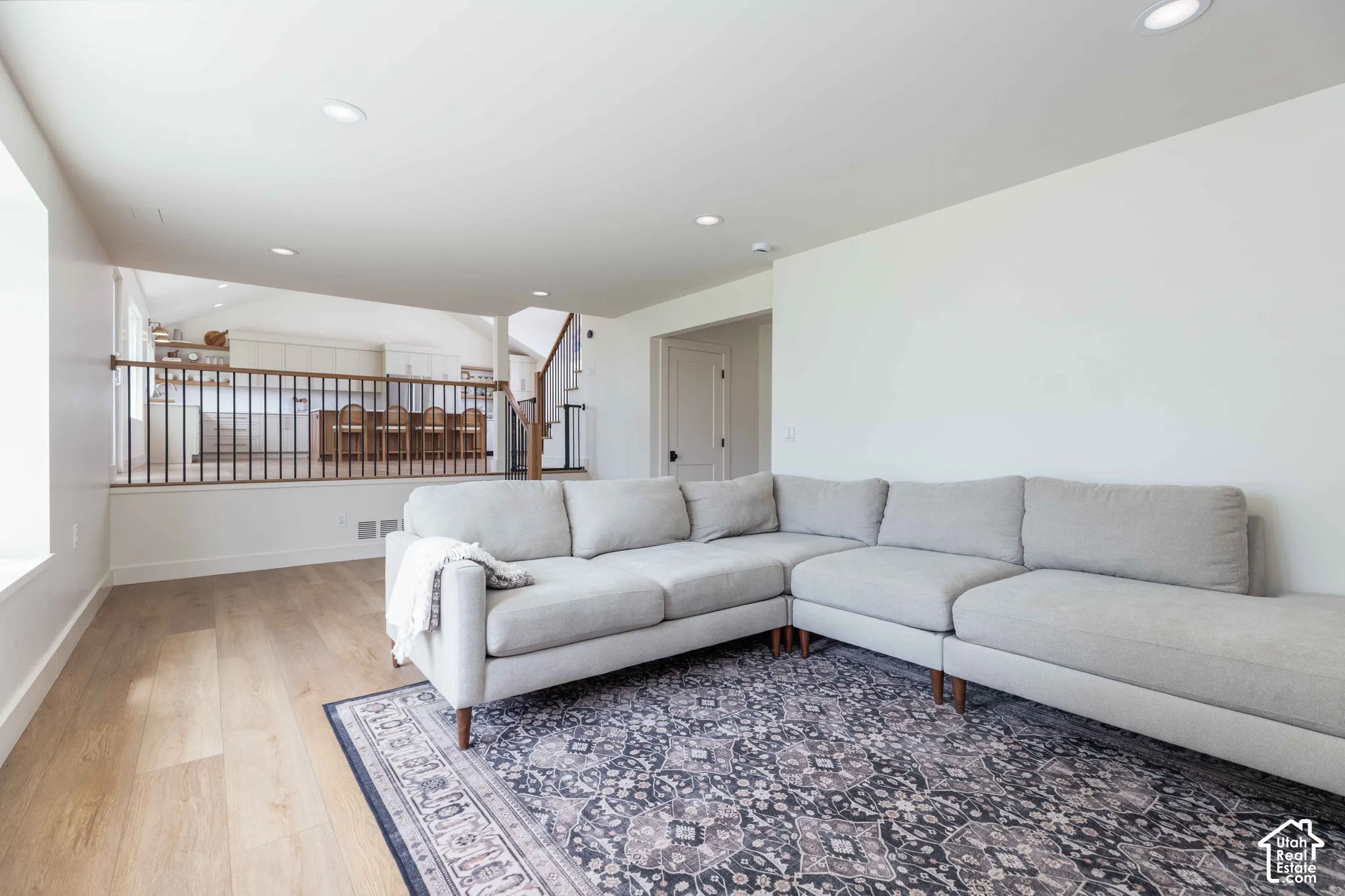 Lower-level living area featuring wood-finish flooring, recessed lighting, and a white color palette