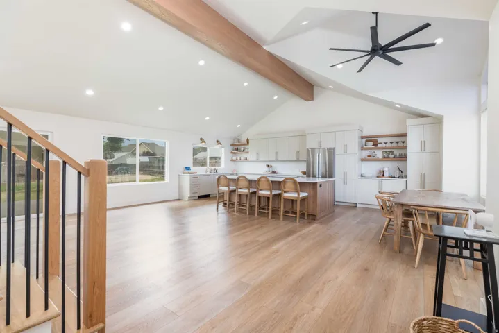 Open concept living space featuring wood-finish flooring, vaulted ceilings with a wood beam, and recessed lighting