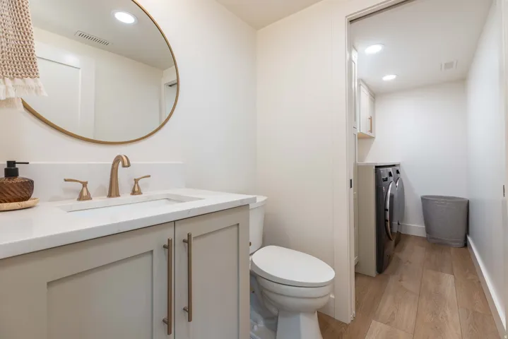 Bathroom vanity featuring a rectangular undermount sink, a bronze-finish faucet, and a light gray cabinet with bronze hardware