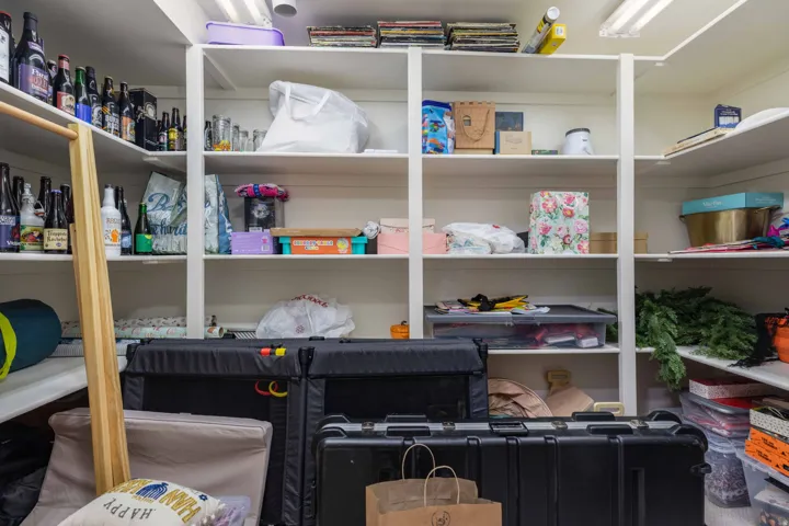 Built-in white shelving system featuring multiple tiers of storage, integrated lighting, and a corner configuration