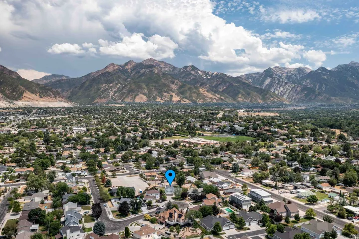 Expansive aerial perspective showcasing a residential neighborhood with abundant mature trees and mountainous terrain