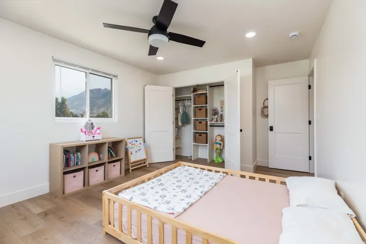 Bedroom featuring wood-finish flooring, a contemporary ceiling fan, recessed lighting, and a window with mountain scenery