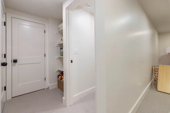 White interior doors with black hardware, recessed shelving, neutral wall paint, white baseboards, and carpeted flooring